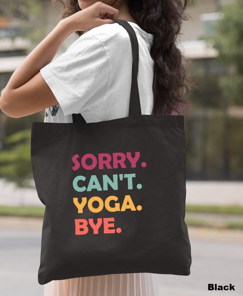 Puede incluir: Bolsa de lona negra con el texto "SORRY. CAN'T. YOGA. BYE." en letras de colores.