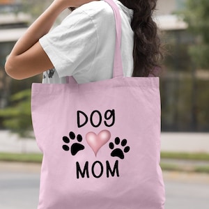 May include: Light pink canvas tote bag with black text that reads "Dog Mom" and a pink heart with black paw prints on either side of the heart.