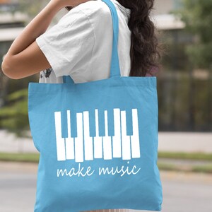 May include: Light blue canvas tote bag with white piano keys and the text "make music".