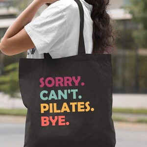 May include: Black canvas tote bag with the text "SORRY. CAN'T. PILATES. BYE." in colorful letters.