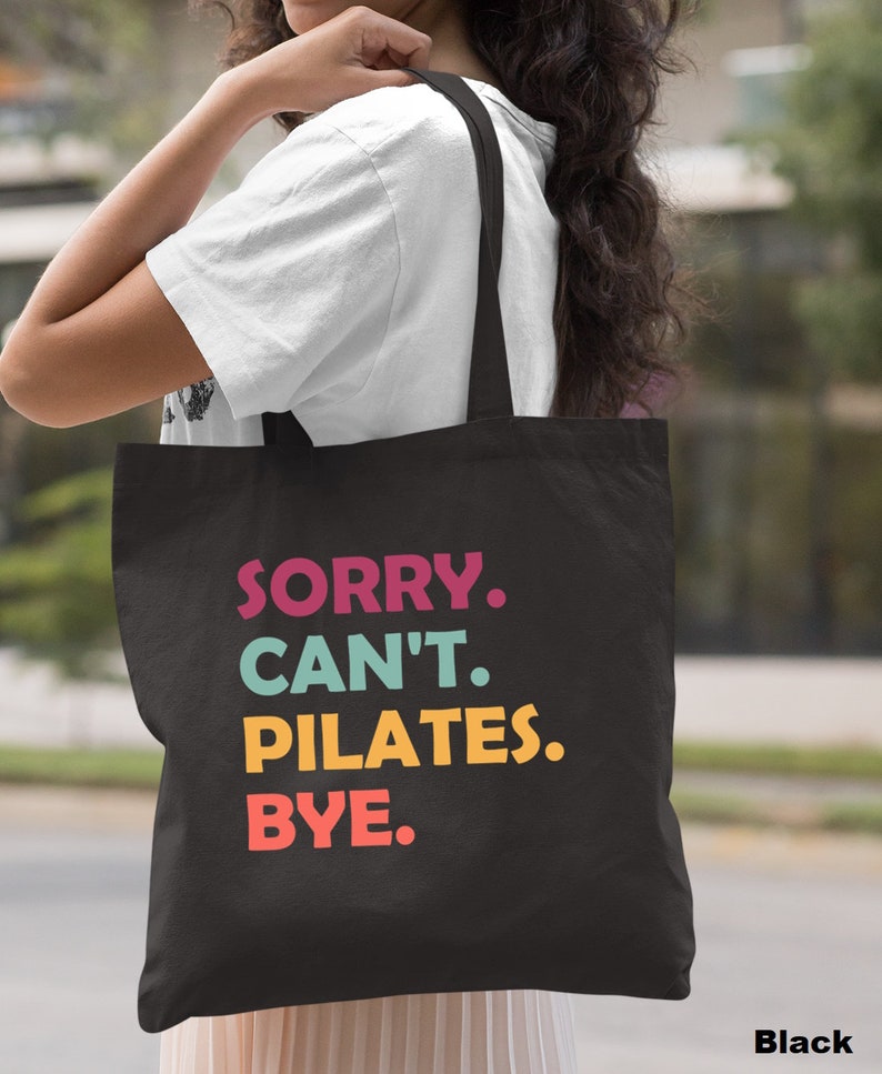 May include: Black canvas tote bag with the text "SORRY. CAN'T. PILATES. BYE." in colorful letters.