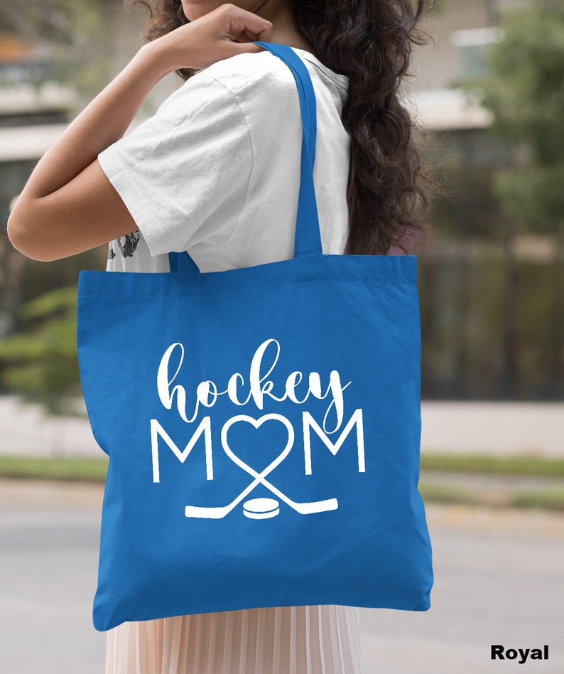 May include: A royal blue tote bag with white text that reads "hockey MOM" with a heart in place of the "O". The bag also features a white hockey stick and puck graphic.