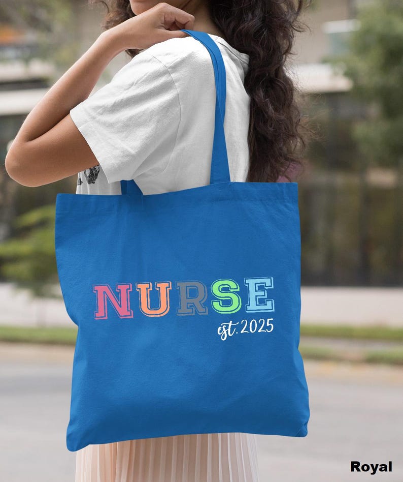 May include: A royal blue tote bag with the word "NURSE" in rainbow colours and the text "est. 2025" in white.