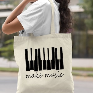 May include: A natural canvas tote bag with black piano keys and the text "make music".