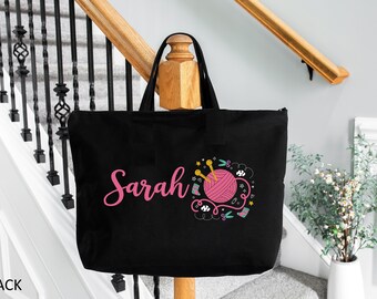 May include: Black tote bag with a pink yarn ball and knitting needles design. The bag has the name "Sarah" printed in pink.