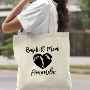 May include: A natural canvas tote bag with black text that reads "Baseball Mom Amanda" and a black baseball heart graphic.