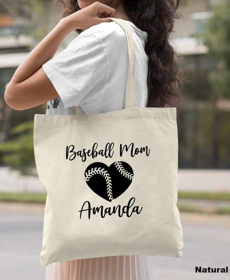 May include: A natural canvas tote bag with black text that reads "Baseball Mom Amanda" and a black baseball heart graphic.