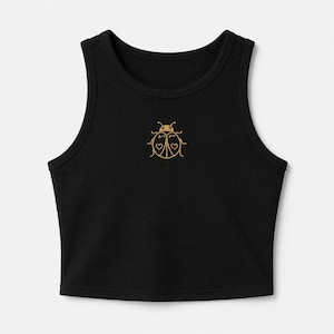 May include: Black crop top with a scoop neck and a gold embroidered ladybug design on the front. The ladybug has heart-shaped details. The top is sleeveless and made of a soft material.