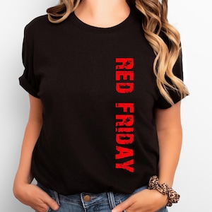 Może przedstawiać: Czarny T-shirt z napisem "RED FRIDAY" nadrukowanym pionowo na czerwono po prawej stronie koszulki.