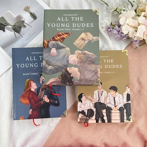May include: Three books titled "All The Young Dudes" are displayed. The covers feature illustrations of people and text. The books have gold corner accents and red ribbon bookmarks. The text on the covers includes "Book Two: Years 5-7" and "Book Three: T".