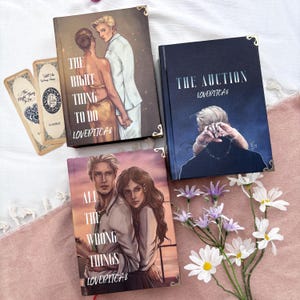 May include: A white ceramic mug with a black handle and the text "But First, Coffee" in a black, handwritten-style font. The mug is on a white surface.