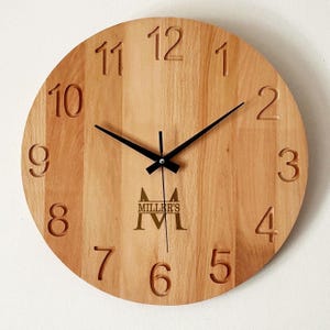 May include: A round wooden clock with carved numerals and black hands. The clock face is light brown with a logo that reads "MILLER'S". The clock is a decorative item.