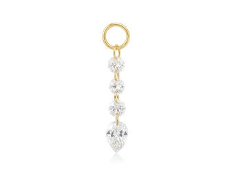 May include: A gold-colored earring charm with a dangling design. The charm features four clear, sparkling gemstones: three round and one pear-shaped. The charm has a small circular loop at the top for attachment.