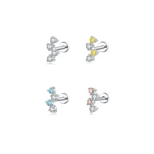 May include: Four silver-colored stud earrings with a cluster of gemstones. Each earring features a different color combination: clear, yellow, light blue, and pink. The gemstones are arranged in a decorative pattern.