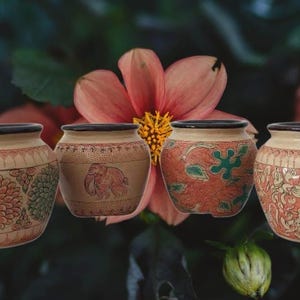 May include: Four decorative ceramic pots with intricate designs. The pots feature floral, elephant, and abstract patterns in shades of red, green, and brown. Each pot has a black rim and a cream-colored base.