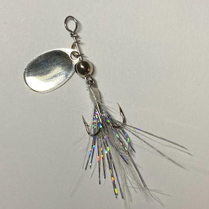 May include: Silver fishing lure with a white feather and iridescent accents.