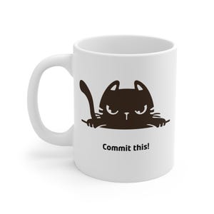 Può includere: Tazza in ceramica bianca con un disegno di gatto dei cartoni animati marrone scuro e la scritta "Commit this!". Il gatto ha un'espressione arrabbiata. La tazza ha un manico curvo.