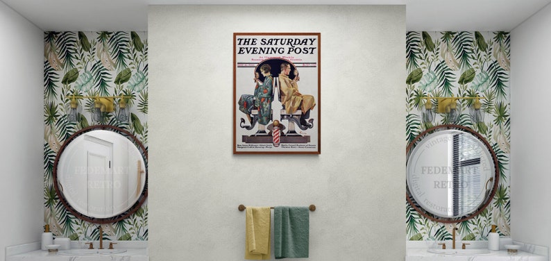 May include: A bathroom interior with two sinks and mirrors, each with a gold-toned faucet. The walls are covered in a tropical leaf wallpaper. A framed vintage magazine cover with the text "The Saturday Evening Post" hangs on the wall above the sinks.