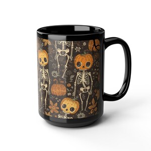 May include: A black ceramic mug featuring a repeating pattern of skeletons with pumpkin heads. The design includes orange pumpkins, skeletal figures, and small floral elements set against a dark brown background. The mug has a handle on the right side.