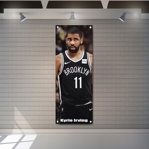 Könnte beinhalten: Ein schwarz-weißes Basketballtrikot mit dem Text "Brooklyn" und der Nummer "11" auf der Vorderseite. Das Trikot wird von einem Basketballspieler mit Bart und ernstem Gesichtsausdruck getragen. Der Text "Kyrie Irving" ist unter dem Trikot gedruckt.