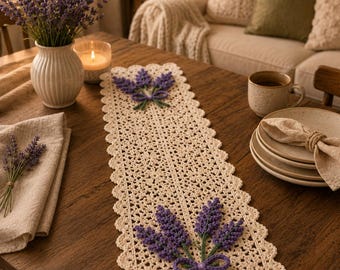 May include: A rectangular cream-coloured crochet table runner featuring a delicate openwork pattern and scalloped edges. Two prominent three-dimensional lavender sprig motifs with purple flowers, green stems, and small bows are attached to the runner.