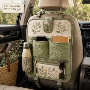 Pode incluir: Um organizador de assento de carro acolchoado em verde sálvia com bordados florais, vários bolsos, um suporte de rede para garrafa e um compartimento com fecho. O organizador inclui uma aba superior com mola e alças ajustáveis.