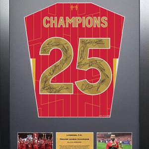 Op de afbeelding: Ingelijst kunstwerk met een rood en goud voetbalshirt met het woord "CHAMPIONS" en het nummer "25". Het shirt is gesigneerd en ingelijst met extra afbeeldingen en tekst, waaronder "Liverpool F.C." en "Premier League Champions".