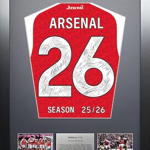 Può includere: Maglia dell'Arsenal incorniciata, rossa con dettagli bianchi, con il numero 26 e le firme dei giocatori. Mostra la scritta "ARSENAL". La cornice è nera, con due foto e una targa sottostante.