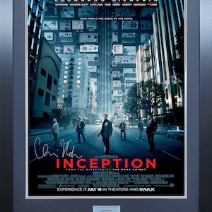 Può includere: Un poster del film Inception, con Leonardo DiCaprio. Il poster presenta una città con edifici impilati uno sull'altro, e un gruppo di persone che cammina per strada. Il testo sul poster recita "Inception" e "Dal regista di The Dark Knight".