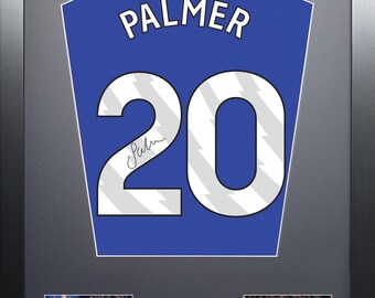 Op de afbeelding: Een ingelijst blauw en wit voetbaltenue met de naam "PALMER" en het nummer "20" op de rug. Het tenue is gesigneerd door Cole Palmer en bevat twee foto's van hem tijdens het voetballen.