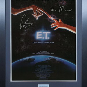 Könnte beinhalten: Ein Filmplakat für den Film E.T. Der Außerirdische. Das Plakat zeigt ein blaues und grünes Bild der Erde mit einer roten und orangefarbenen außerirdischen Hand, die sich nach einer menschlichen Hand ausstreckt. Der Text auf dem Plakat lautet "Sein Abenteuer auf der Erde" und "E.T. Der Außerirdische".