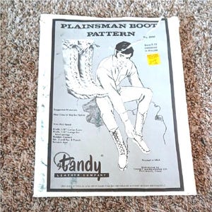 May include: A white paper pattern packet for Plainsman Boots, No. 2690, featuring a black and white illustration of a person lacing up tall boots. The text includes "Sizes 5-13 contained in this pak," "Suggested Materials," and "Tandy Leather Company."