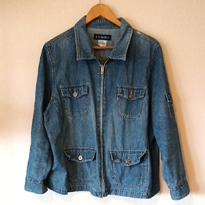 May include: A medium-wash denim jacket with a zip-up front and four front pockets. The jacket has a collared neckline and long sleeves. The brand name "LA Blues" is visible on the label. The jacket is hanging on a wooden hanger.