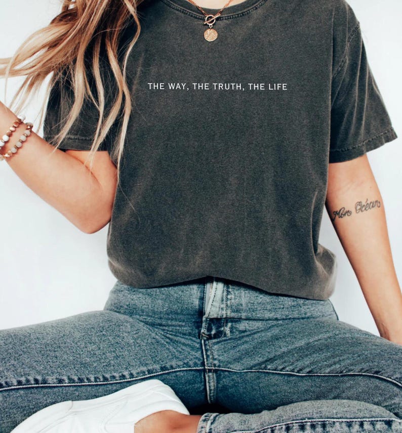 Może przedstawiać: Szary t-shirt z nadrukiem "THE WAY, THE TRUTH, THE LIFE" na przodzie. Koszulkę nosi osoba w niebieskich dżinsach.