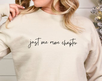 May include: A cream-colored sweatshirt with the text "just one more chapter" in black script.