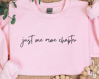 May include: Pink sweatshirt with the text "just one more chapter" in black script.