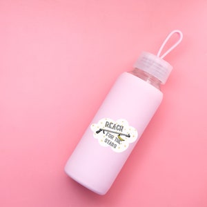 Puede incluir: Una botella de agua rosa con una pegatina blanca que dice "Reach for the stars" y un dibujo animado de una mano alcanzando una luna creciente con una estrella encima.