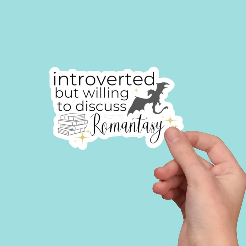 May include: A white sticker with a black silhouette of a dragon and a stack of books. The text on the sticker reads "introverted but willing to discuss Romantasy".