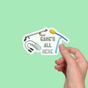 May include: A sticker featuring a blue, yellow and white design. It includes a cleaning tool, a sponge, a banana and a chain with two hooks. The text on the sticker reads "Gang's All Here".