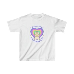 May include: White t-shirt with a rainbow heart and a paw print inside. The text "Cats say that stuttering is ok" is written around the heart.