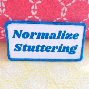 May include: White patch with a blue border and the text "Normalize Stuttering" in blue.