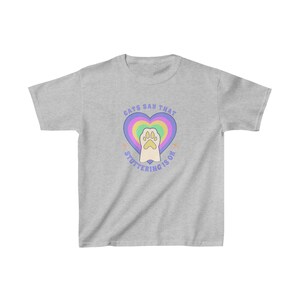 May include: A gray t-shirt with a rainbow heart and a paw print inside. The text "Cats say that stuttering is ok" is written around the heart.