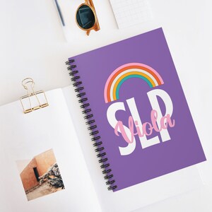 May include: Purple spiral notebook with a rainbow and the text "SLP Viola" in white and pink letters.