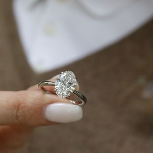 Puede incluir: Un anillo de plata con un gran diamante de forma ovalada.