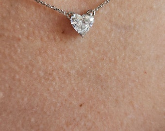 Puede incluir: Un collar de cadena de plata con un colgante de diamante en forma de corazón.