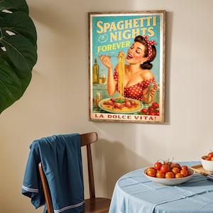 May include: A framed vintage-style poster with the text "Spaghetti Nights Forever" and "La Dolce Vita!" features a woman eating spaghetti. The poster is in a wooden frame and hangs on a beige wall. A table is set with tomatoes and a blue tablecloth.