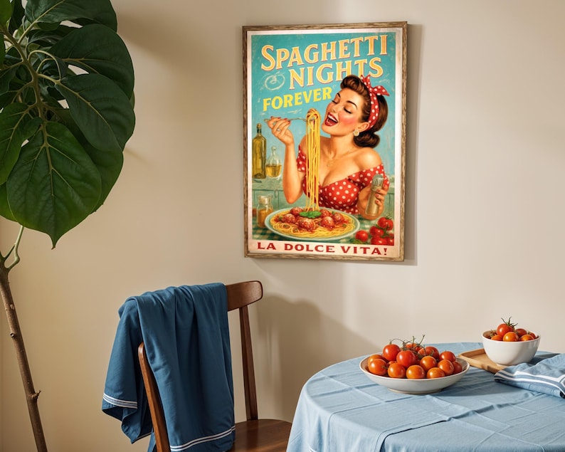 May include: A framed vintage-style poster with the text "Spaghetti Nights Forever" and "La Dolce Vita!" features a woman eating spaghetti. The poster is in a wooden frame and hangs on a beige wall. A table is set with tomatoes and a blue tablecloth.