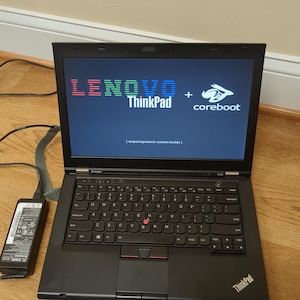 May include: A black Lenovo ThinkPad laptop with a white rabbit logo on the screen. The screen displays the text "LENOVO ThinkPad + coreboot [respectsyoutech custom builds]" in a retro pixelated font.