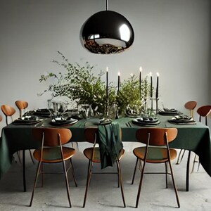 May include: A dark green tablecloth covers a dining table set with six chairs. The table is decorated with a silver pendant light, a centerpiece of greenery, and candles. The chairs are made of wood with a dark brown finish.