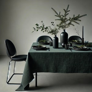 Puede incluir: Un mantel verde oscuro con jarrones negros y vegetación, preparado para una cena con platos y cubiertos negros.